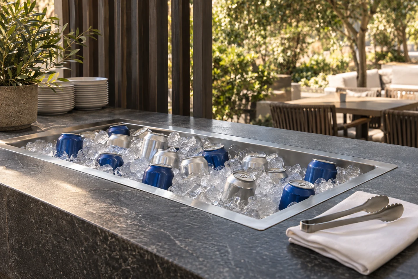Closed navy and silver cans in a stainless-steel ice well beside a terrace dining area